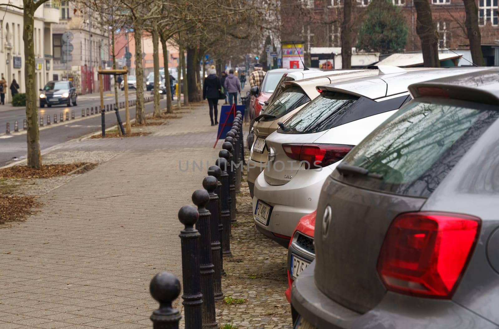 Poznan, Poland - January 20, 2023: Cars parked along the street, people walk along the sidewalk.