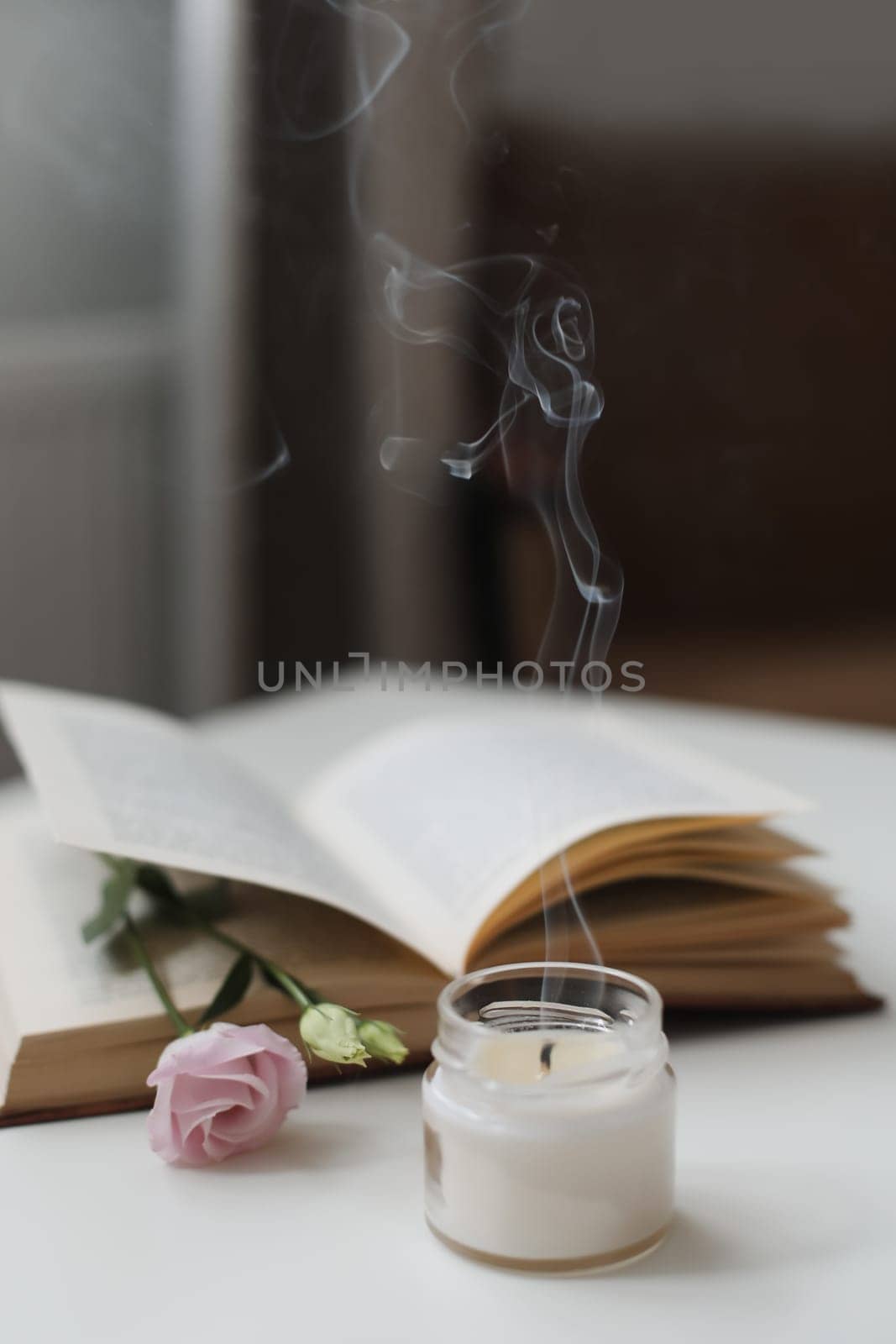 Details of still life in the home interior of living room. Flowers, book, candle. Moody. Cozy spring concept.