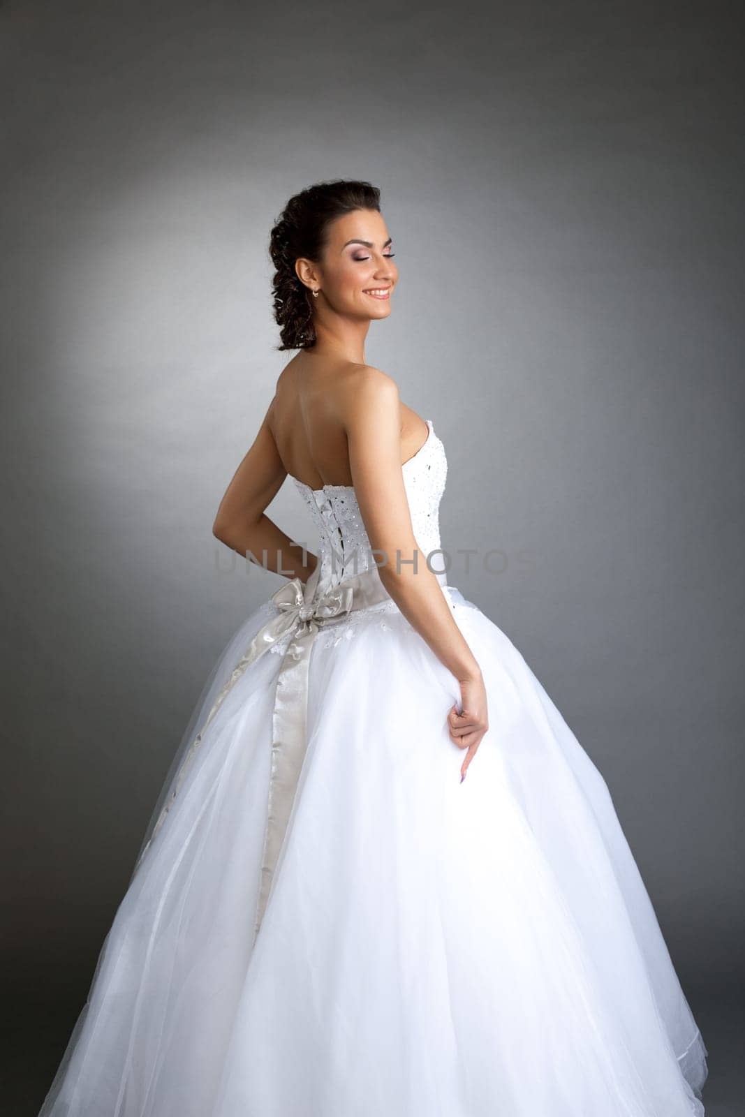 Cheerful model posing in wedding dress on gray background, close-up