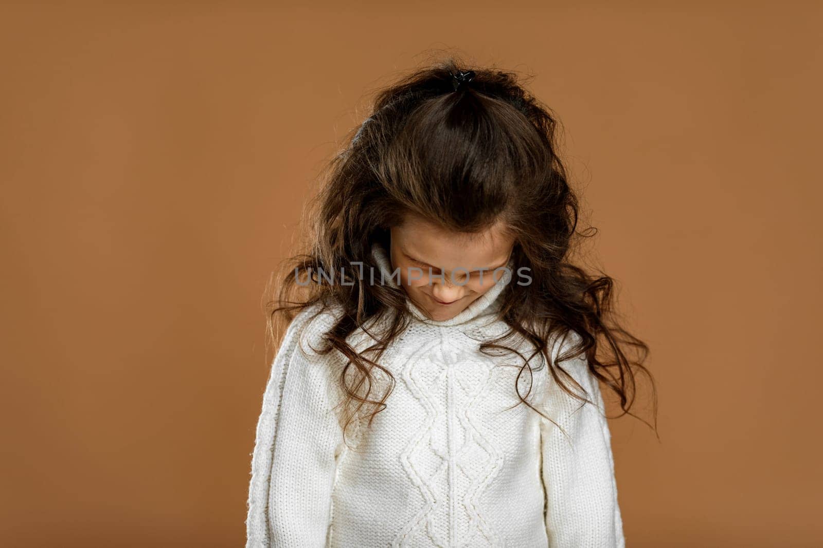 frowned little child girl in white sweater. Human emotions and facial expression