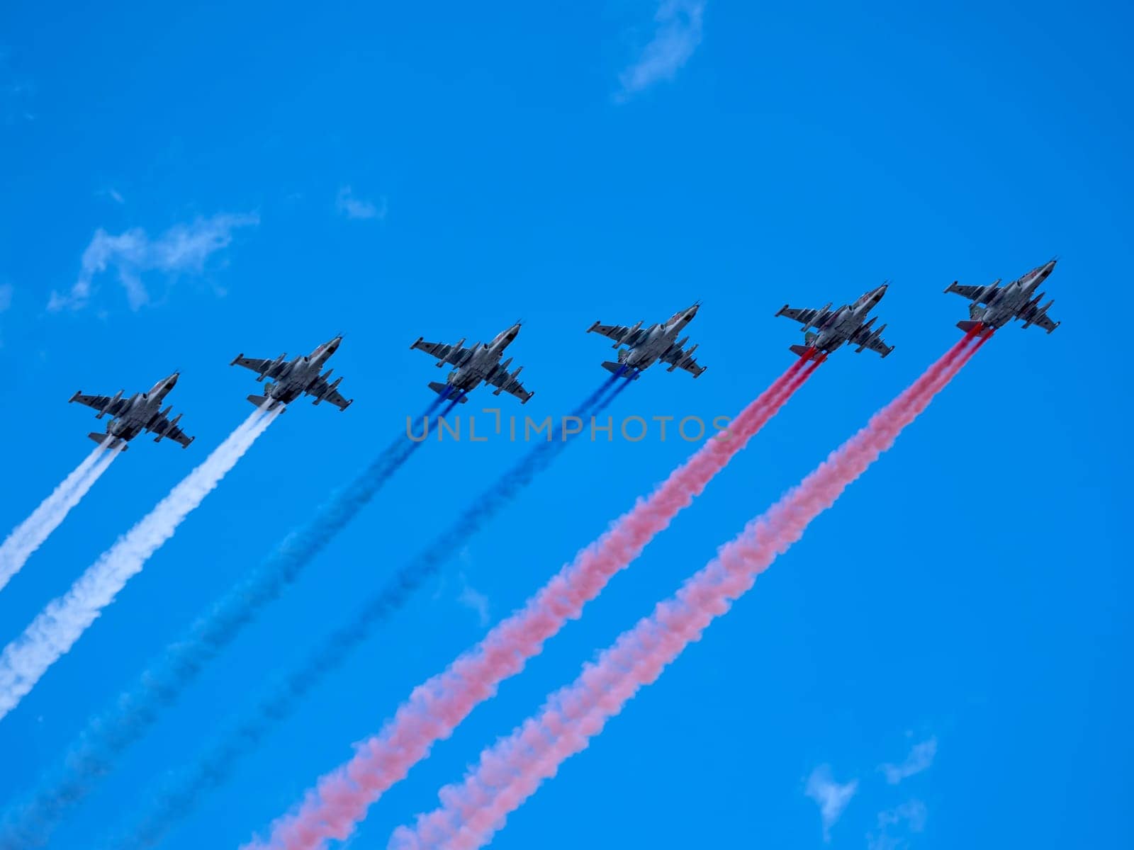 MOSCOW, RUSSIA - MAY 7, 2021: Avia parade in Moscow. Group of Russian fighters Sukhoi Su-25 with painted russian flag in the sky on parade of Victory in World War II in Moscow, Russia