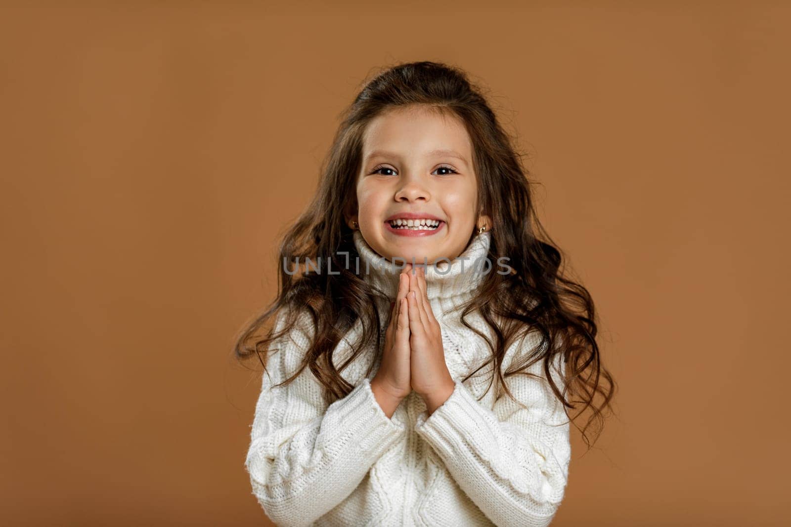 happy beautiful curly little girl in white sweater asking for something. Dream come true