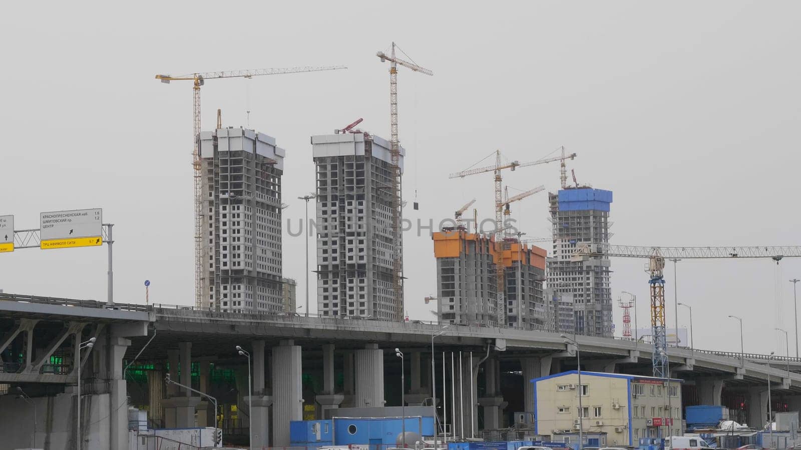 Many of cranes. Tower cranes against blue sky, with clouds.