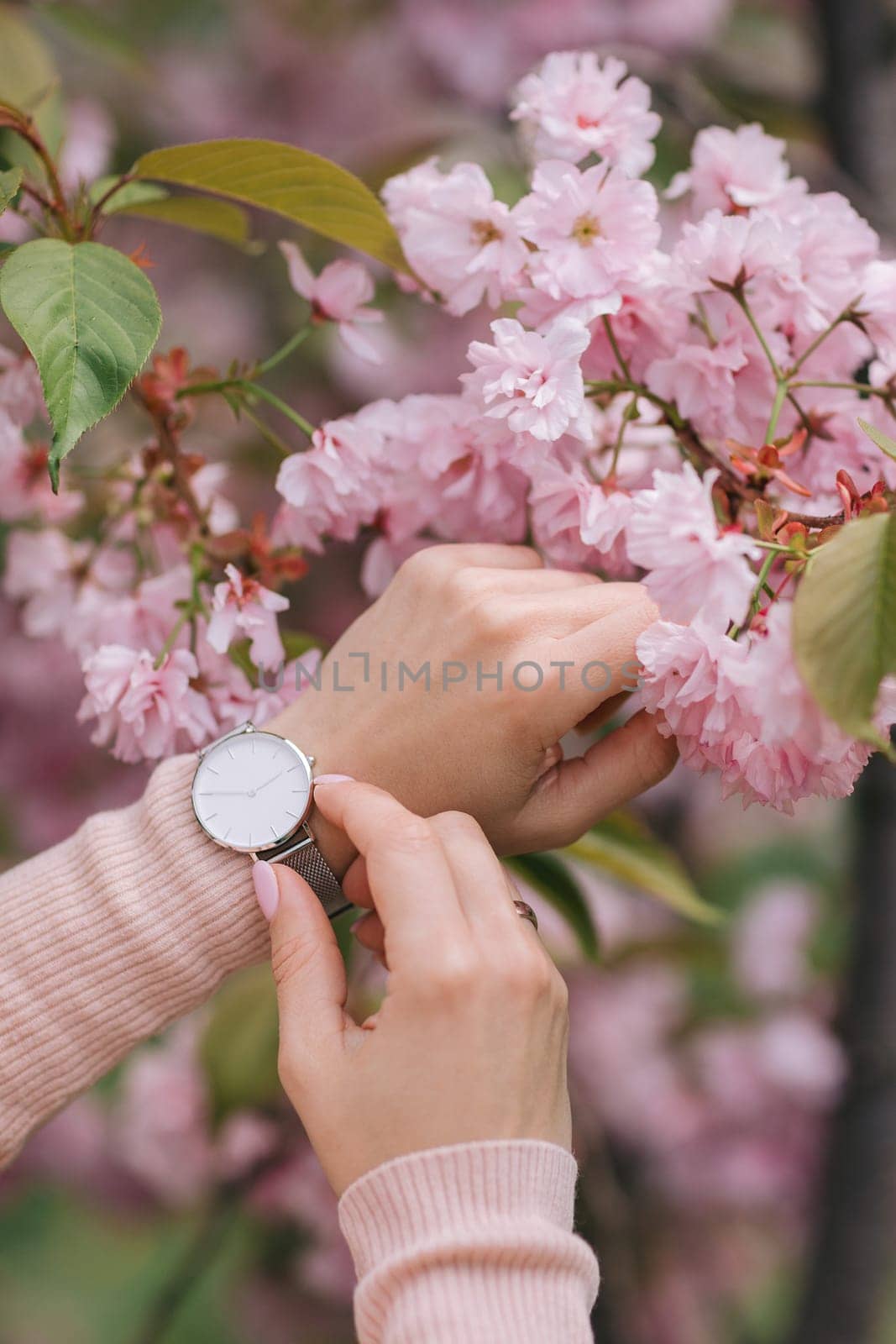 Stylish watch on woman hand on flower background. woman looking at her watch.