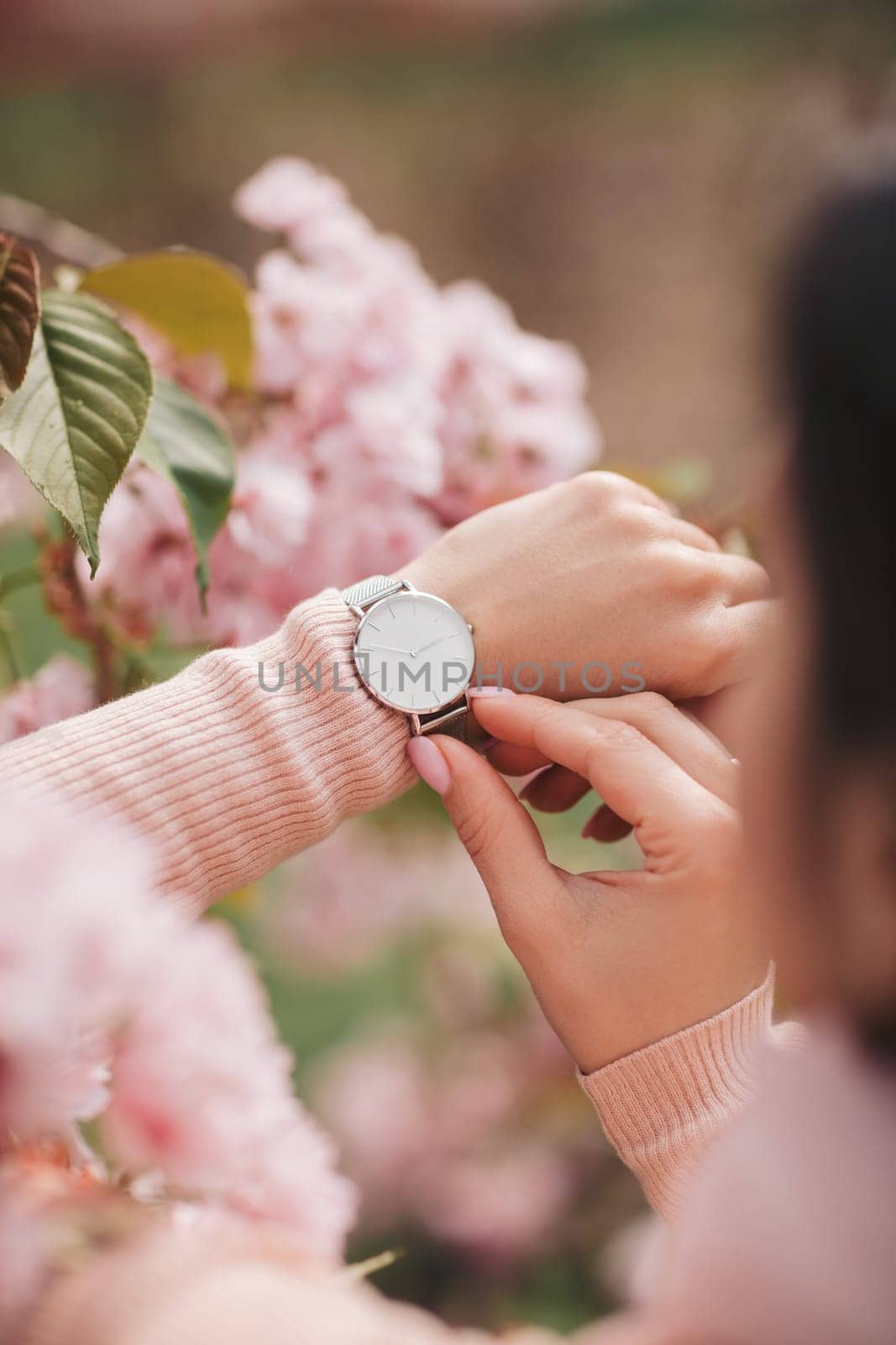 Stylish watch on woman hand on flower background. woman looking at her watch.