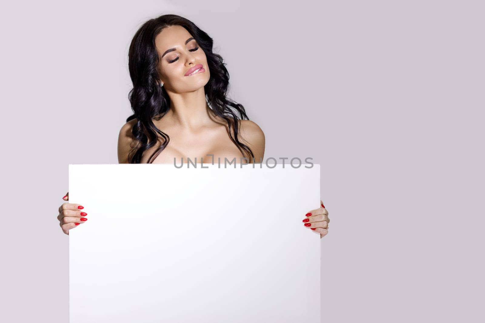 seductive naked brunette woman holding empty board. attractive sexy girl with blank board with copy space