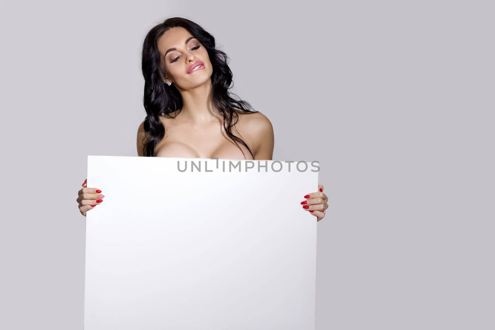 seductive naked brunette woman holding empty board. attractive sexy girl with blank board with copy space
