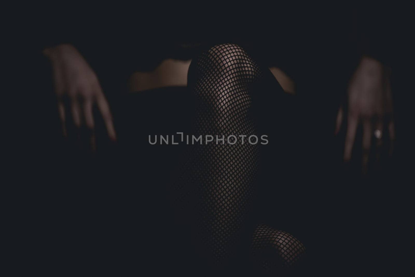 slim sexy woman in black stockings sits on a chair on a black background