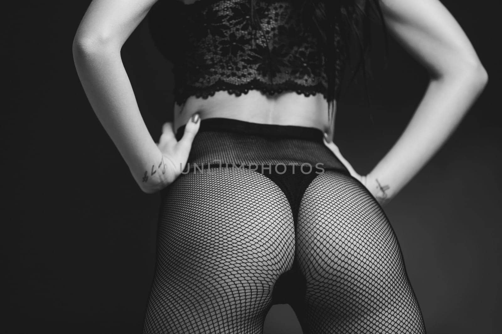 Sexy butt woman in lace black sensual lingerie and pantyhose on black background. Luxury ass in stockings