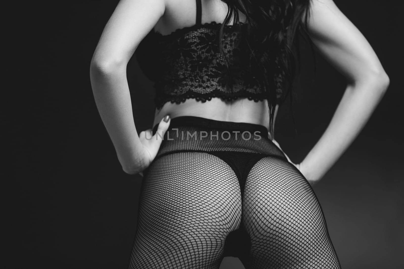 Sexy butt woman in lace black sensual lingerie and pantyhose on black background. Luxury ass in stockings