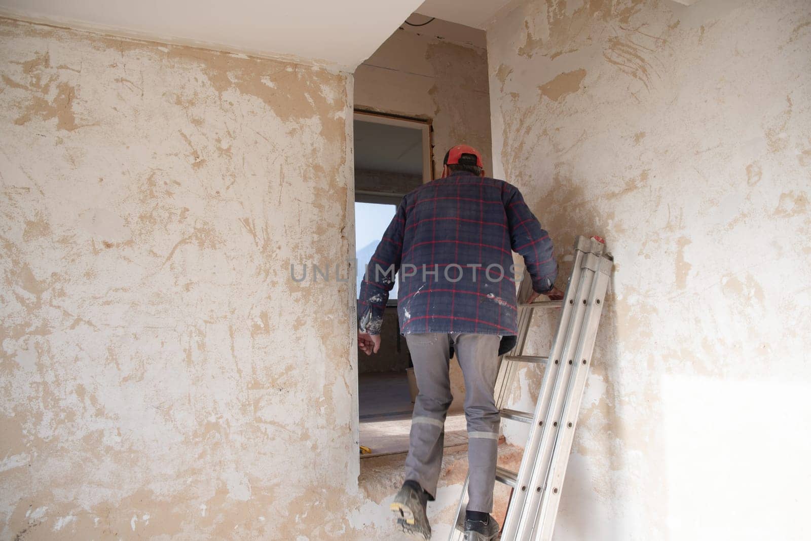 a male builder stands in an apartment near peeling walls and starts repairs in a new house in the middle of an empty room, High quality photo
