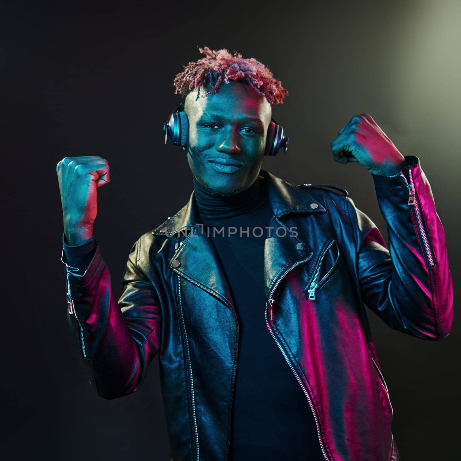 Dancing with headphones on. Futuristic neon lighting. Young african american man in the studio by Standret