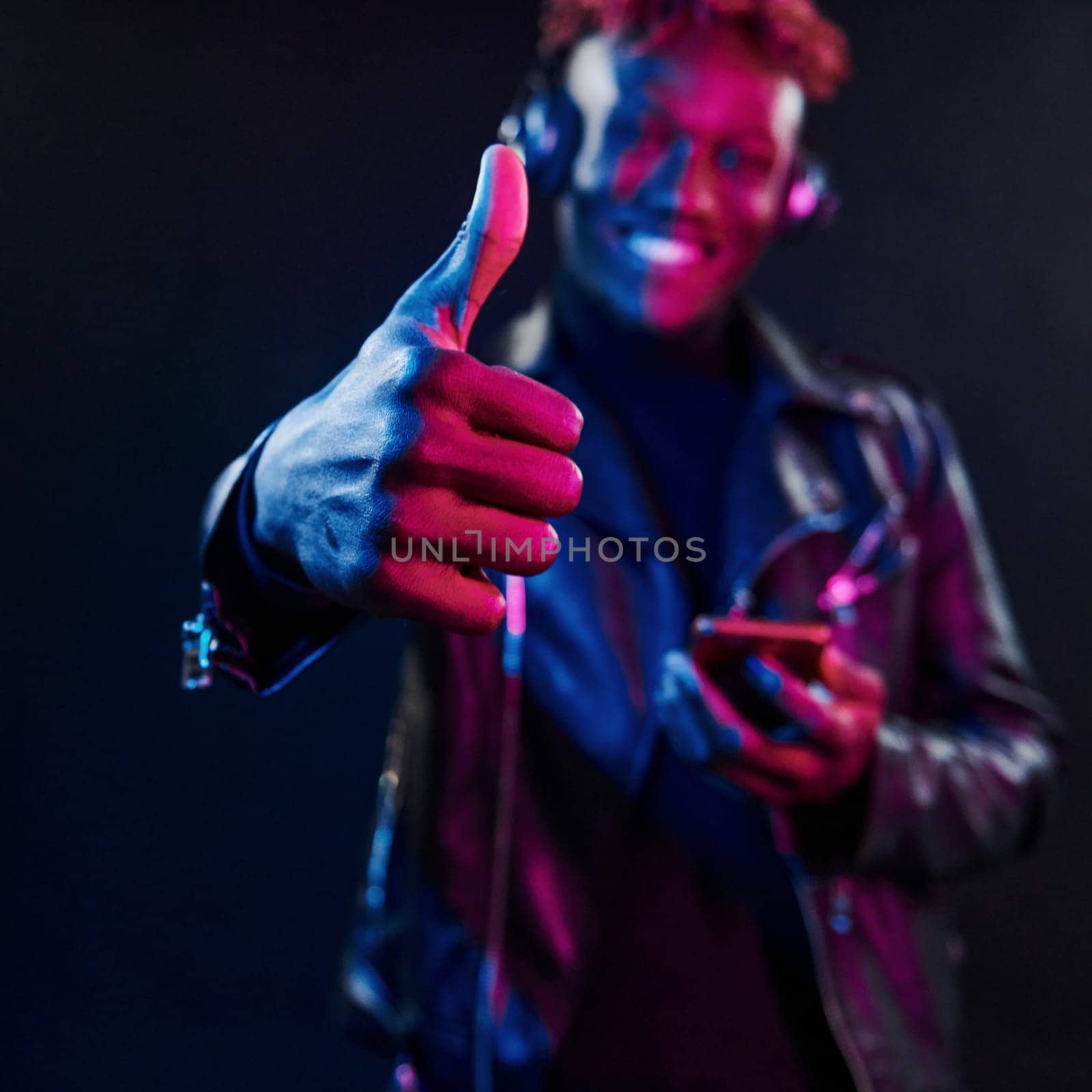 Dancing with headphones on. Futuristic neon lighting. Young african american man in the studio.