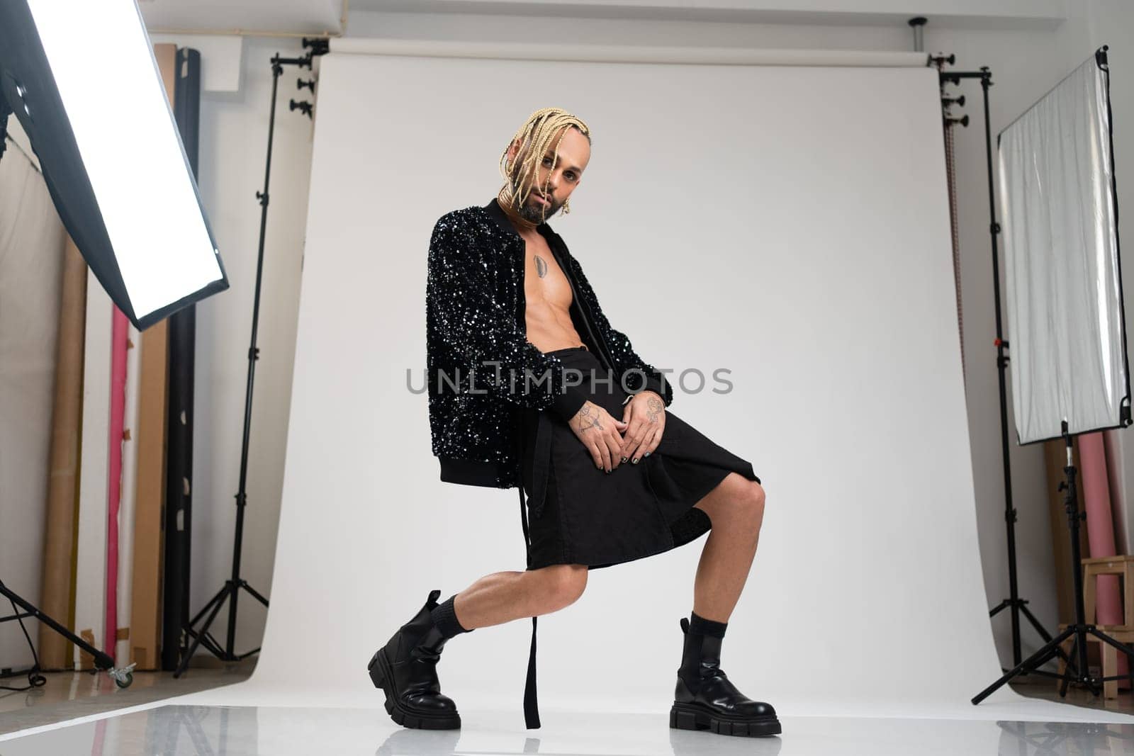 Full length gay man wearing women clothing dancing. Brazilian homosexual male wearing black skirt and boots posing in photo studio on white background. Bearded gay with make up