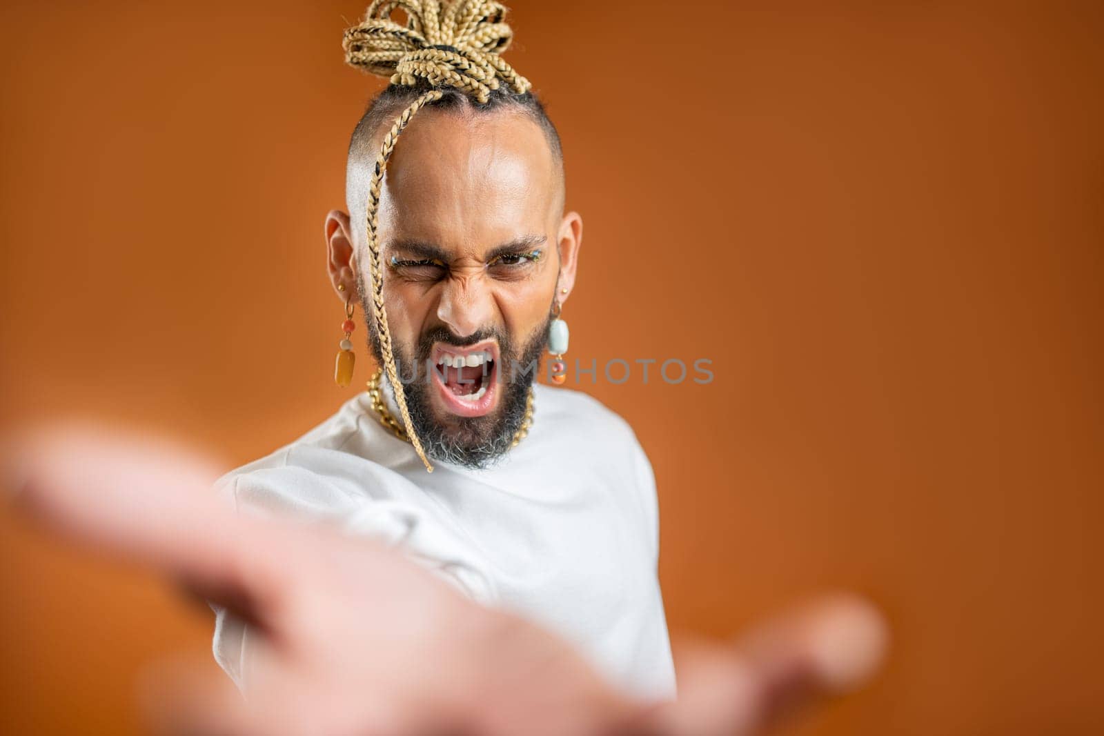 African-american gay with bright make up reaching empty open palm hand toward to camera and scream loud. Mock up advertisement concept. Homosexual serious man outstretching empty hand towards camera.