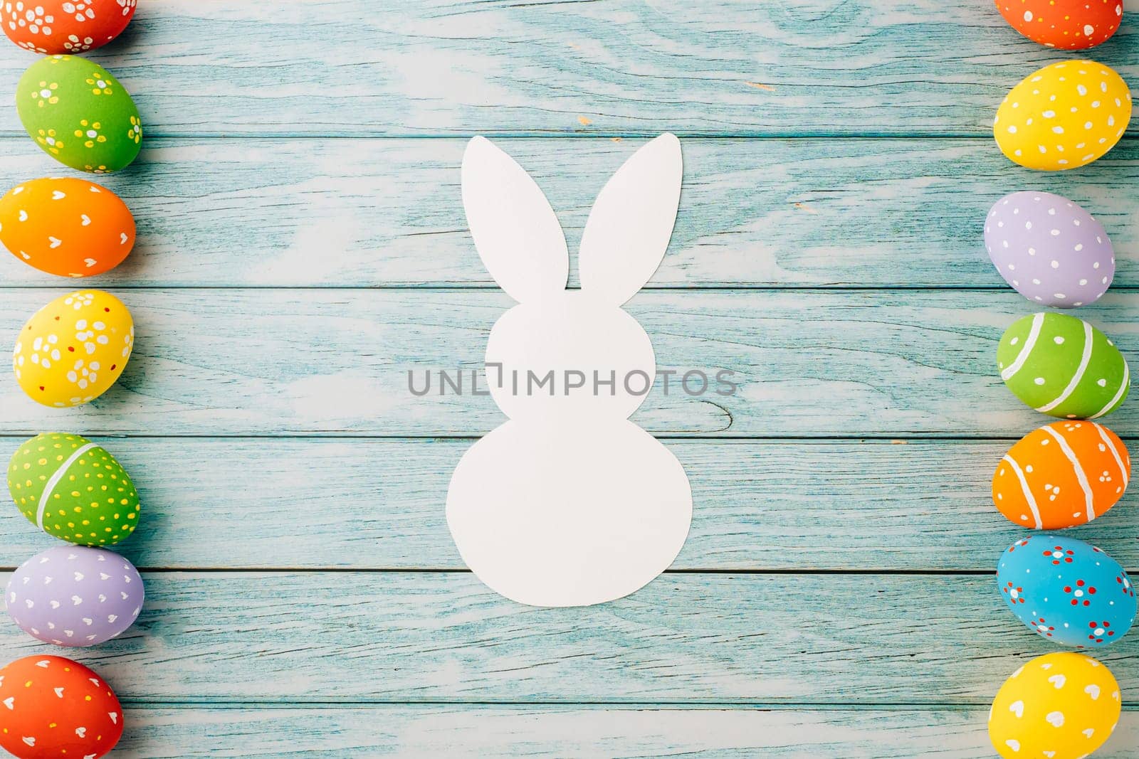 Easter Day Concept. Top view holiday banner background web design white colorful easter eggs and paper bunny rabbit on blue wood background with copy space, celebration greeting, overhead, template