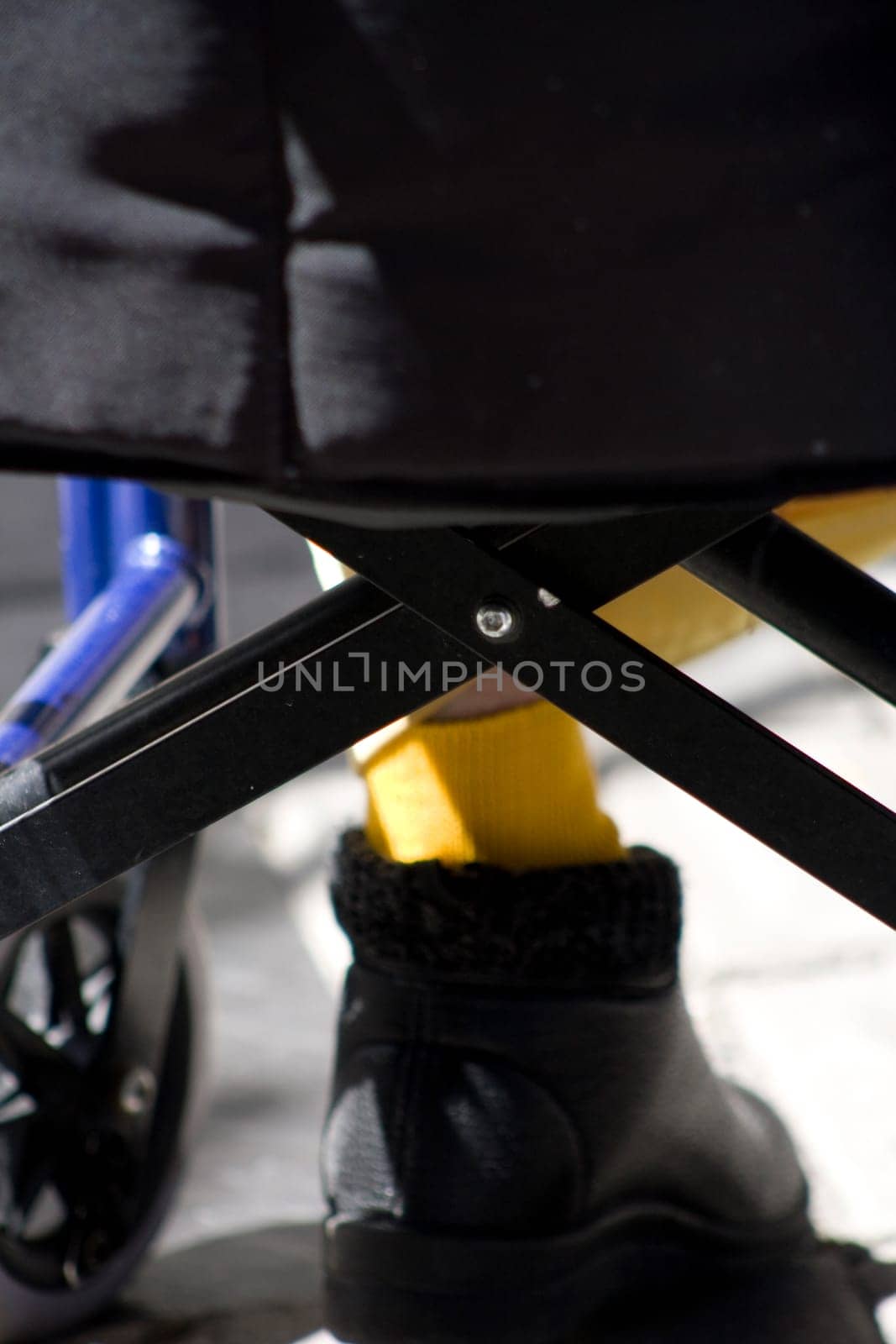wheelchair seen from behind and the foot of an elderly lady sitting in it. concept photography in health and the elderly