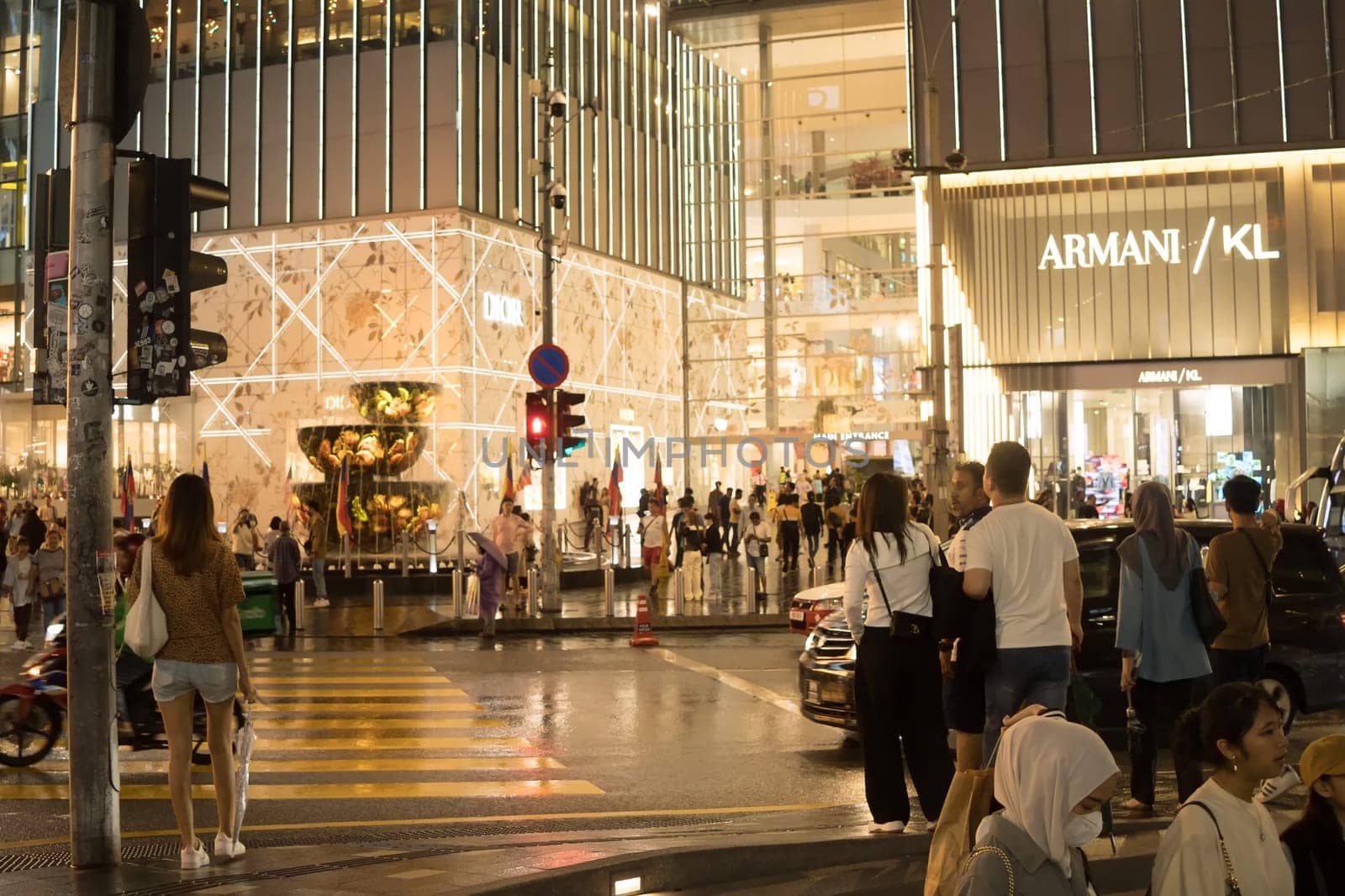 March 2, 2023. Bukit Bintang, Kuala Lumpur. People crossing the street at night when raining. Street Photography.