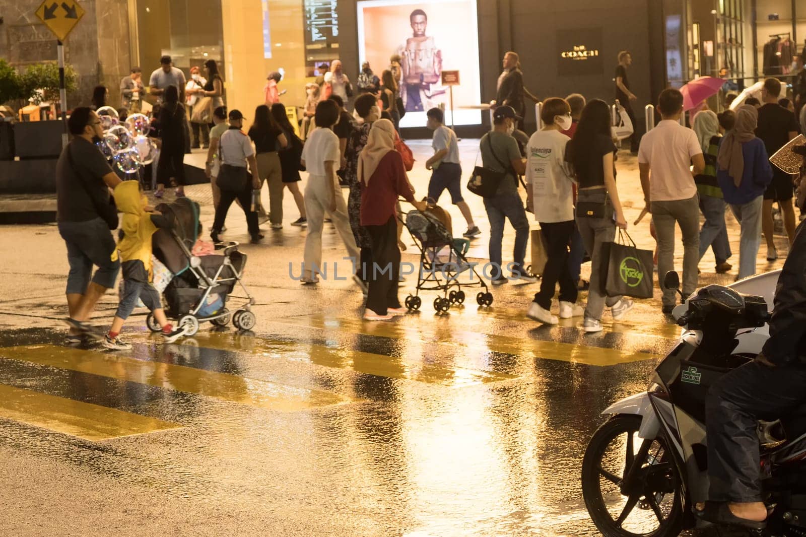 March 2, 2023. Bukit Bintang, Kuala Lumpur. People crossing the street at night when raining. Street Photography.