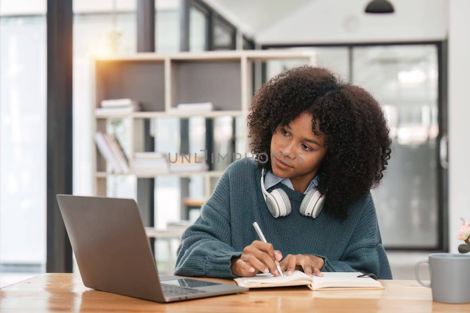 Smiling young african american teen girl wear headphones video calling on laptop. Happy woman student looking at computer screen watching webinar or doing video chat by webcam..