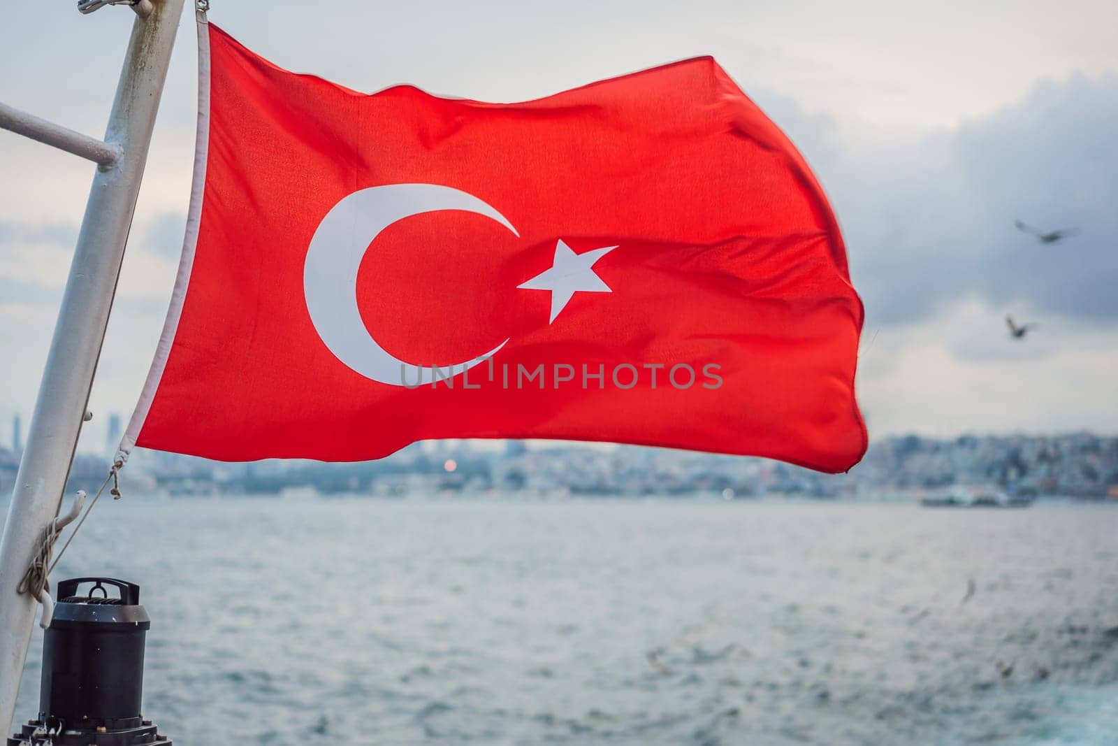 Turkish flag flying in the wind against the background of the sea and the coast.