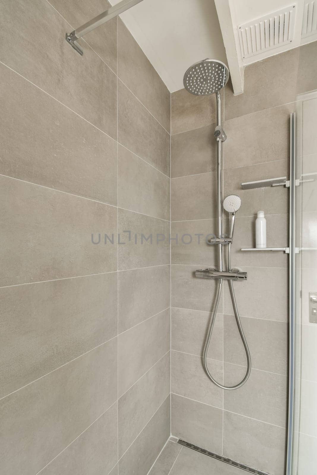 a shower with a shower head in a bathroom by casamedia