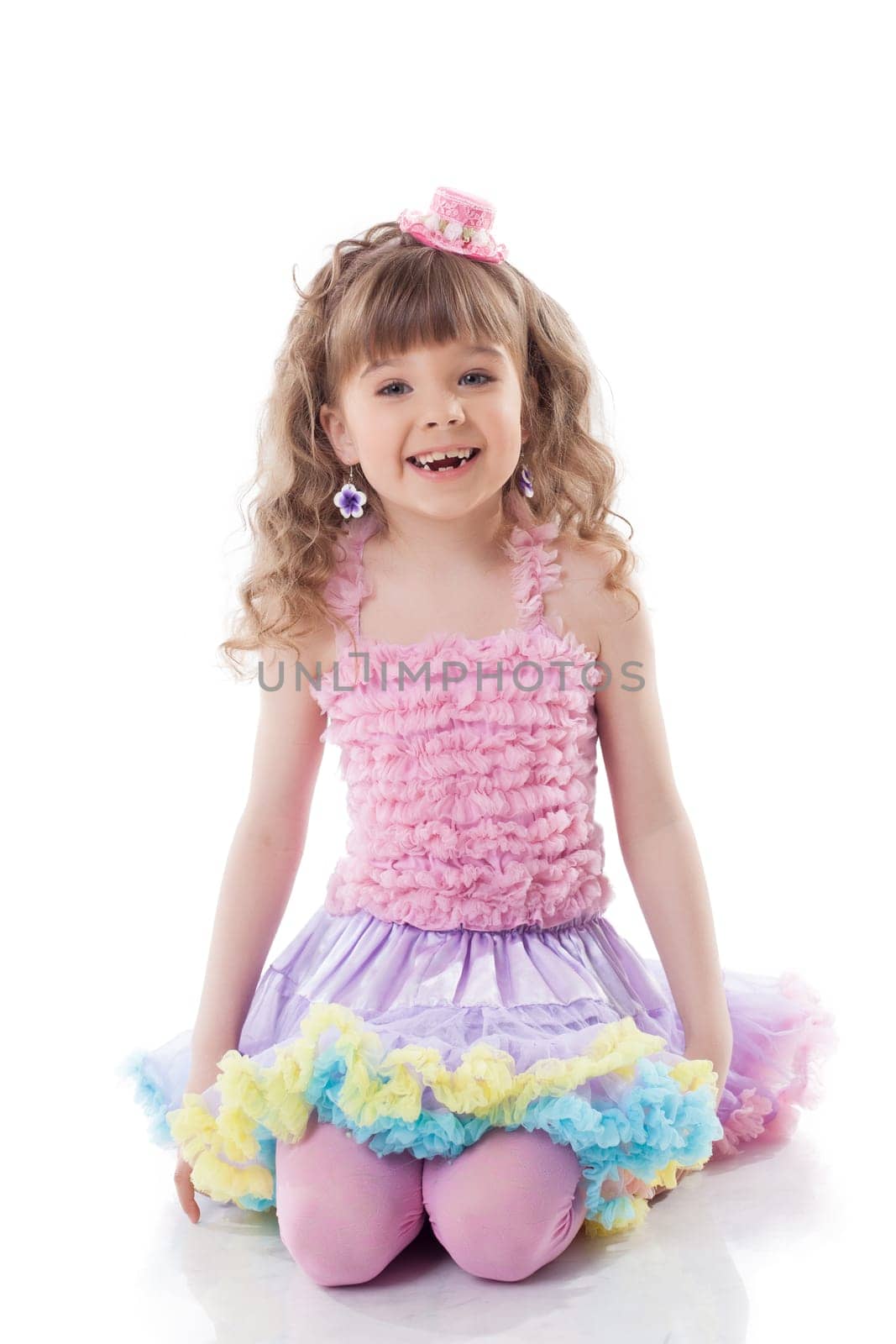 Smiling curly girl posing in candy costume, isolated on white