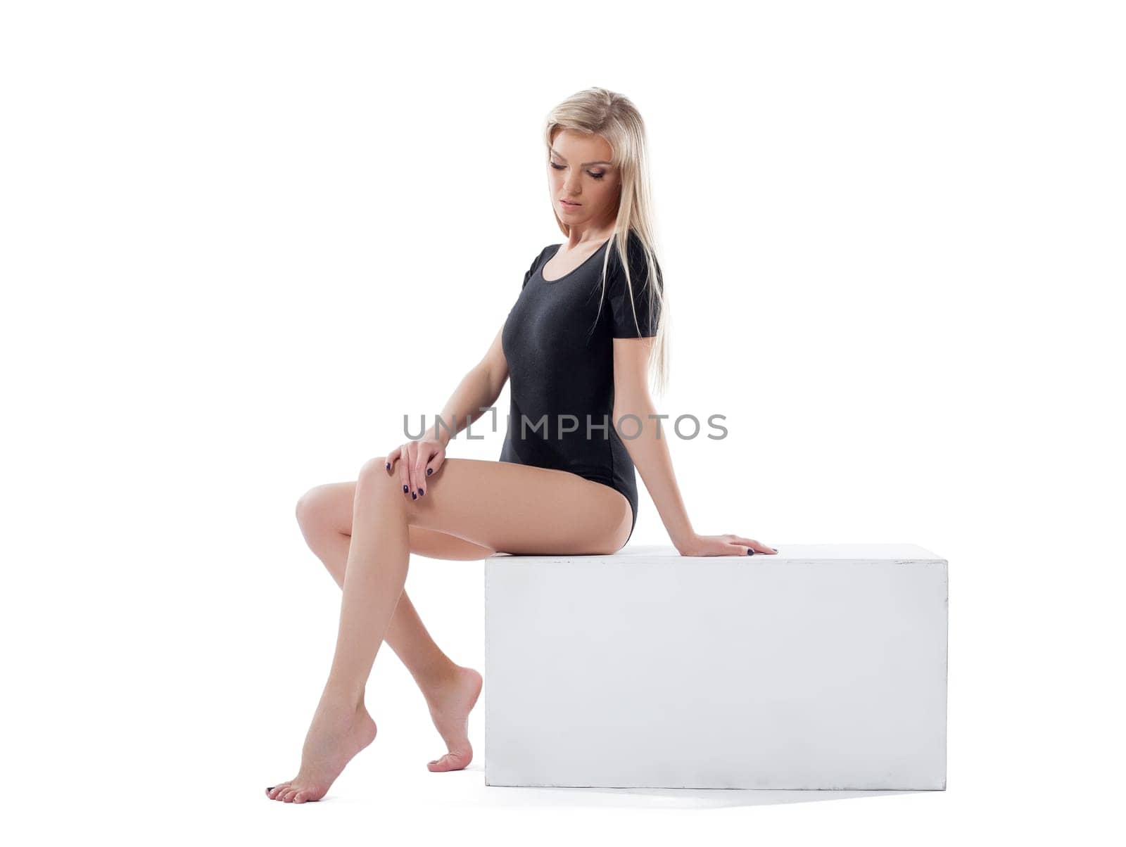 Slim blonde posing barefoot in studio, isolated on white