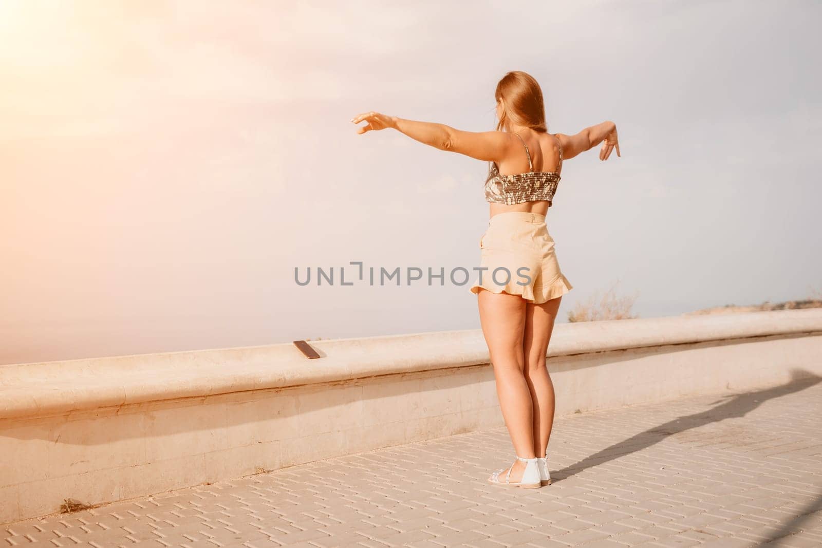 silhouette of a happy woman who dances, spins and raises her hands to the sky. A woman is enjoying a beautiful summer day.