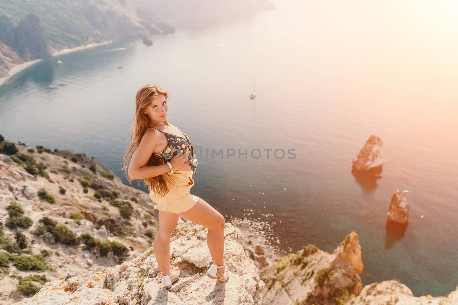 Woman travel sea. Happy tourist taking picture outdoors for memories. Woman traveler looks at the edge of the cliff on the sea bay of mountains, sharing travel adventure journey.