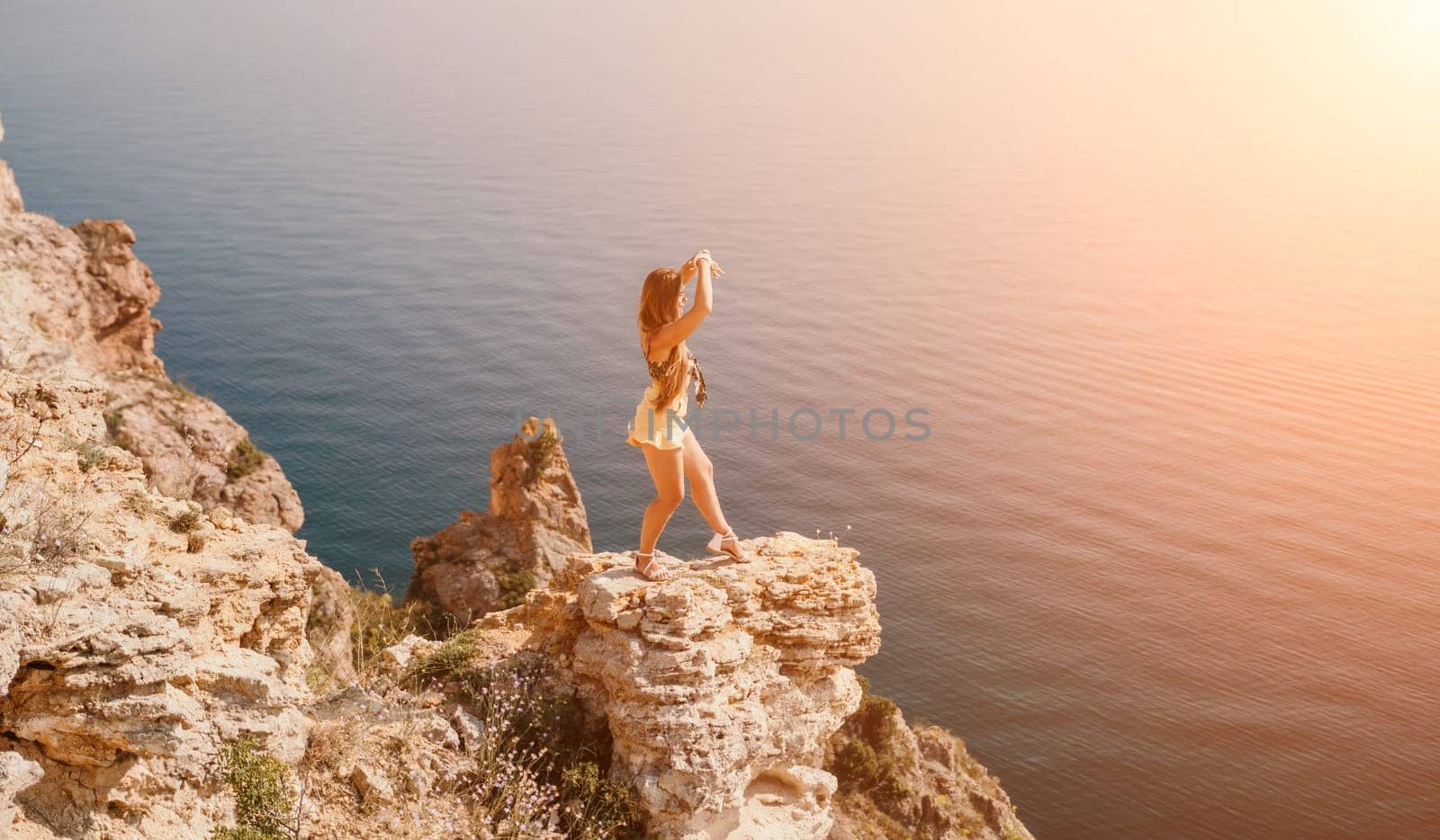 Woman travel sea. Happy tourist taking picture outdoors for memories. Woman traveler looks at the edge of the cliff on the sea bay of mountains, sharing travel adventure journey.