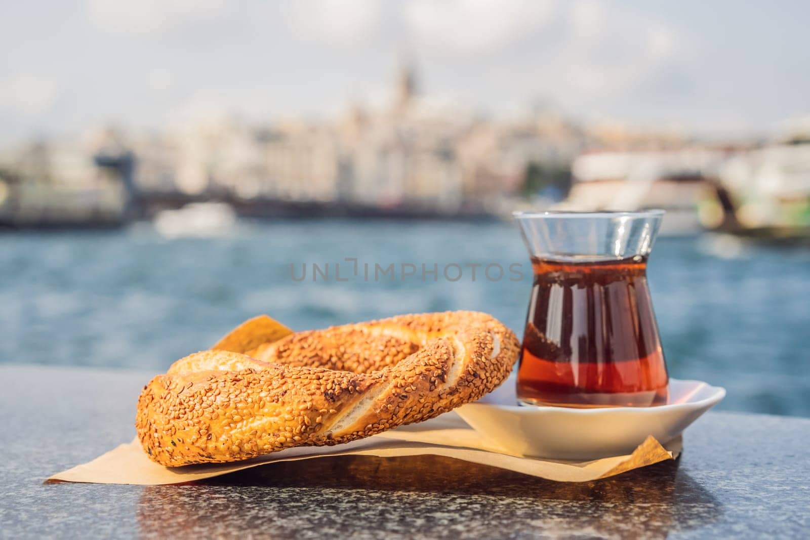 A glass of Turkish tea and bagel Simit against golden horn bay in Istanbul, Turkey. Turkiye.