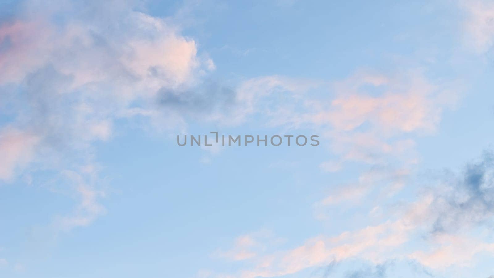 Background of blue sky with pale pink clouds at sunset