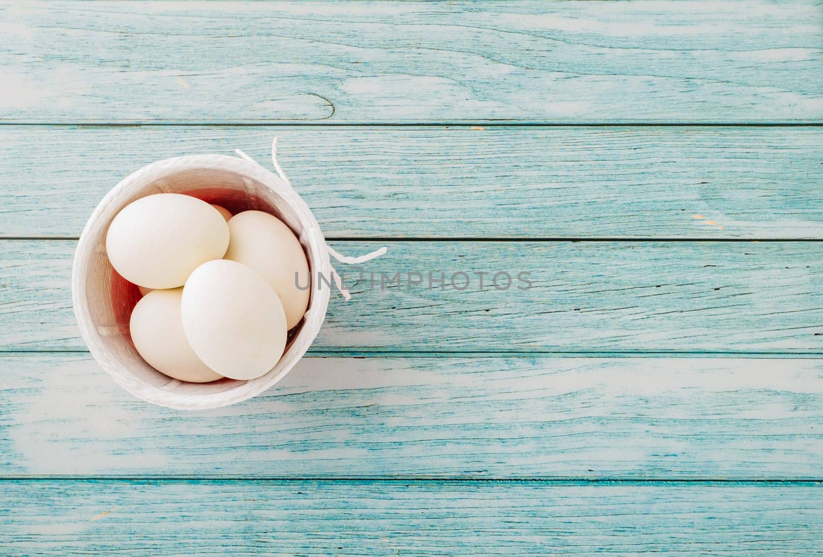 Happy Easter Day Concept. Top view of holiday banner background design white easter eggs and basket on blue wooden background with empty copy space, celebration greeting card