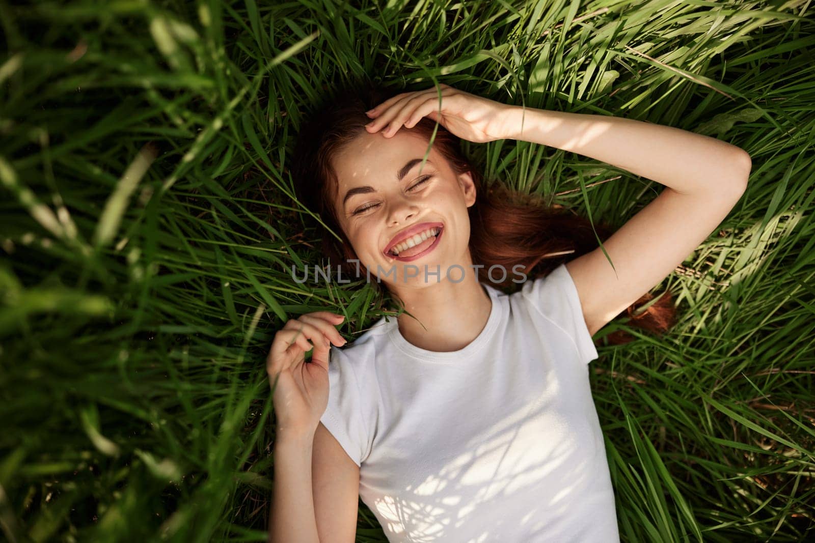 portrait of smiling happy woman with teeth on the grass by Vichizh