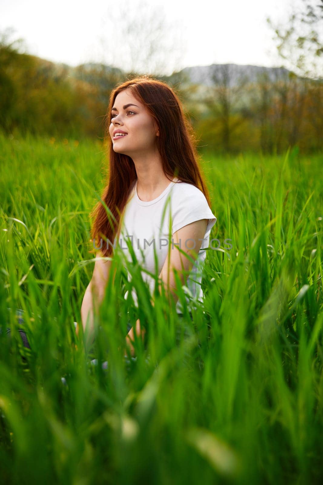 cute, happy woman in white t-shirt midit in green grass by Vichizh
