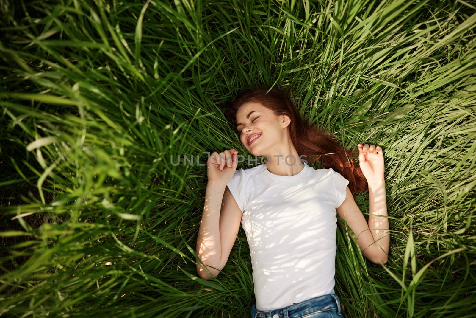 joyful woman resting in tall grass during sunset. High quality photo