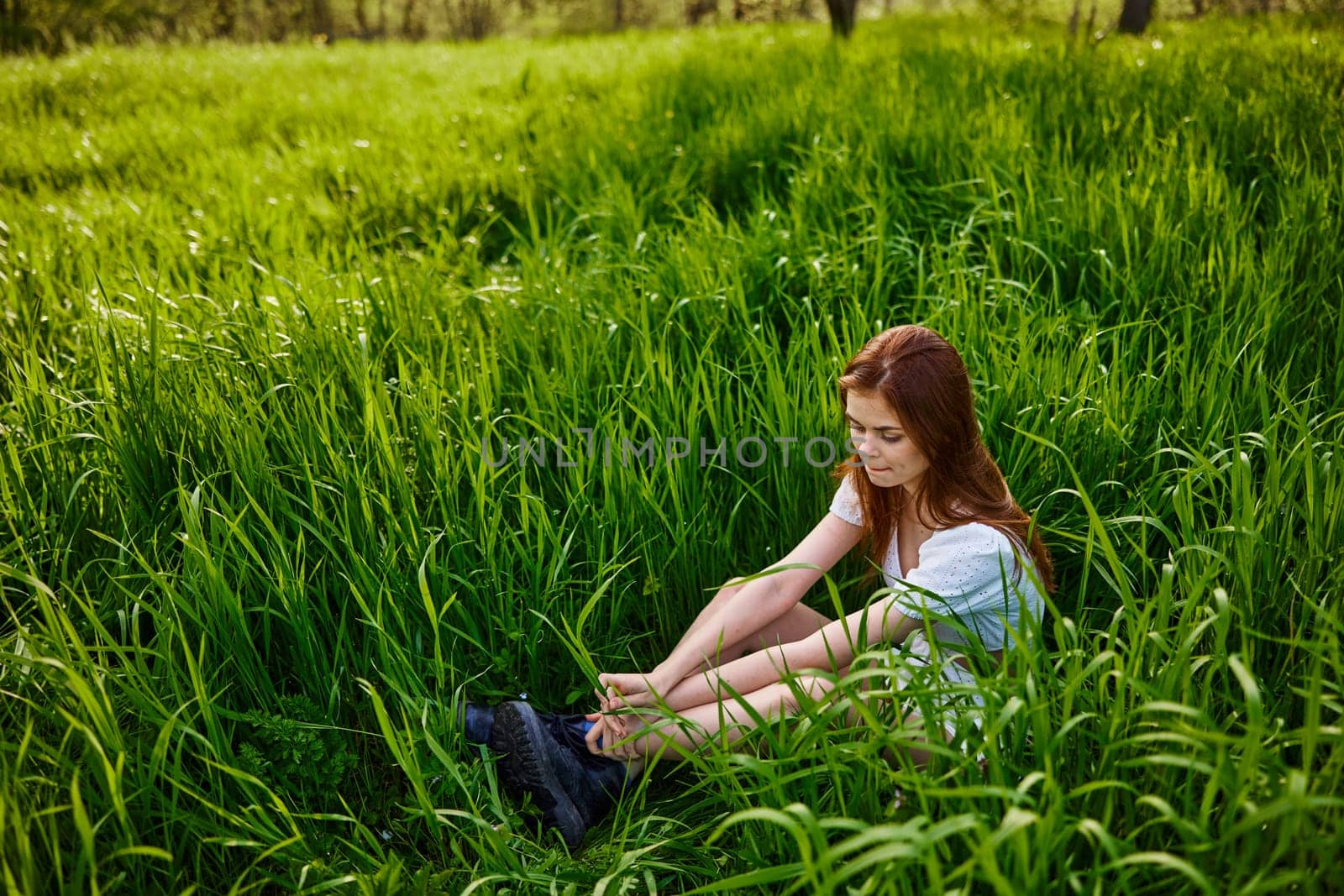 a pretty woman sits in the tall grass enjoying a sunny day and harmony with nature. High quality photo