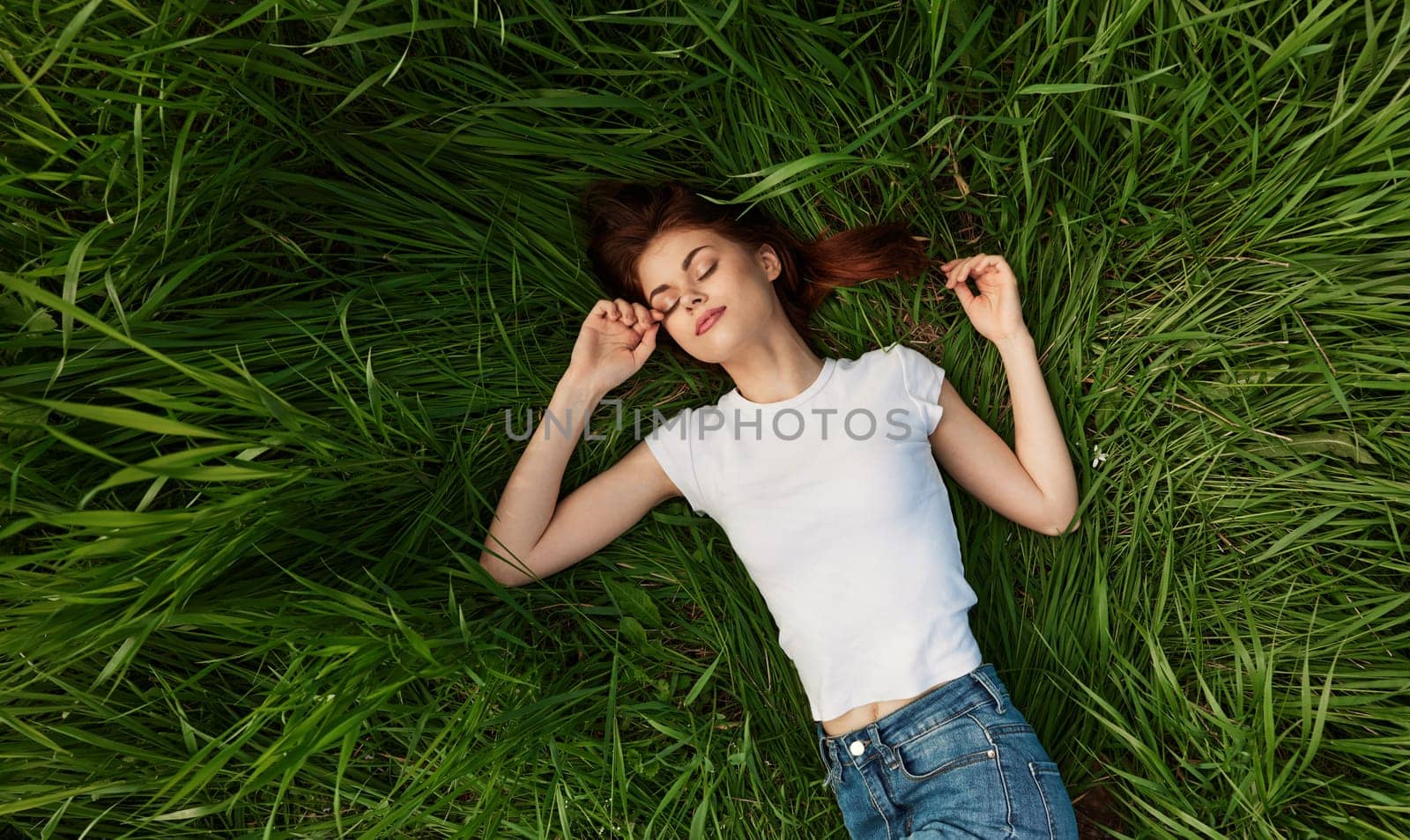 peaceful, happy woman lies in green tall grass. High quality photo