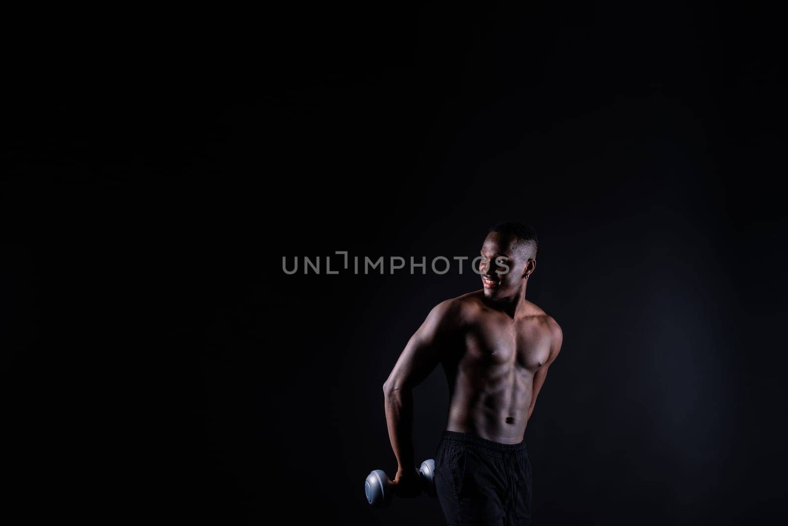 Portrait of a happy african man with dumbbells over red and black background by Zelenin