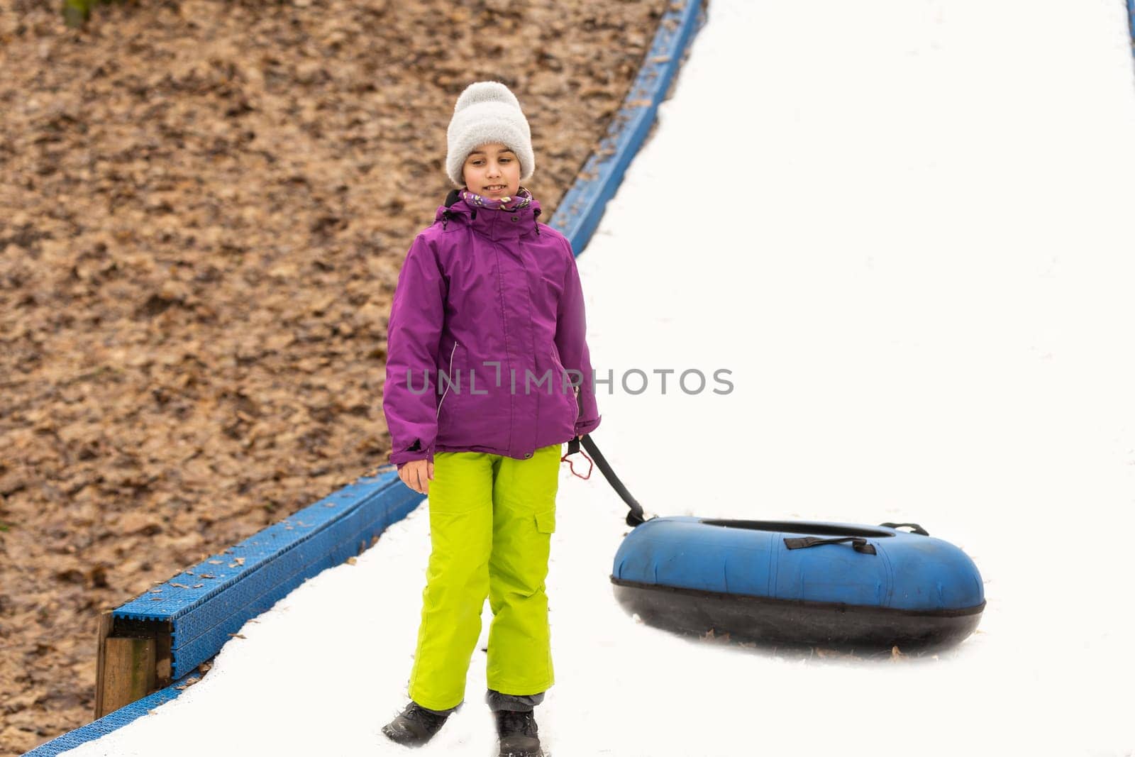 Active girl sliding down the hill on snow tube. Cute little happy child having fun outdoors in winter on sledge . Healthy excited kid tubing snowy downhill, family winter time.