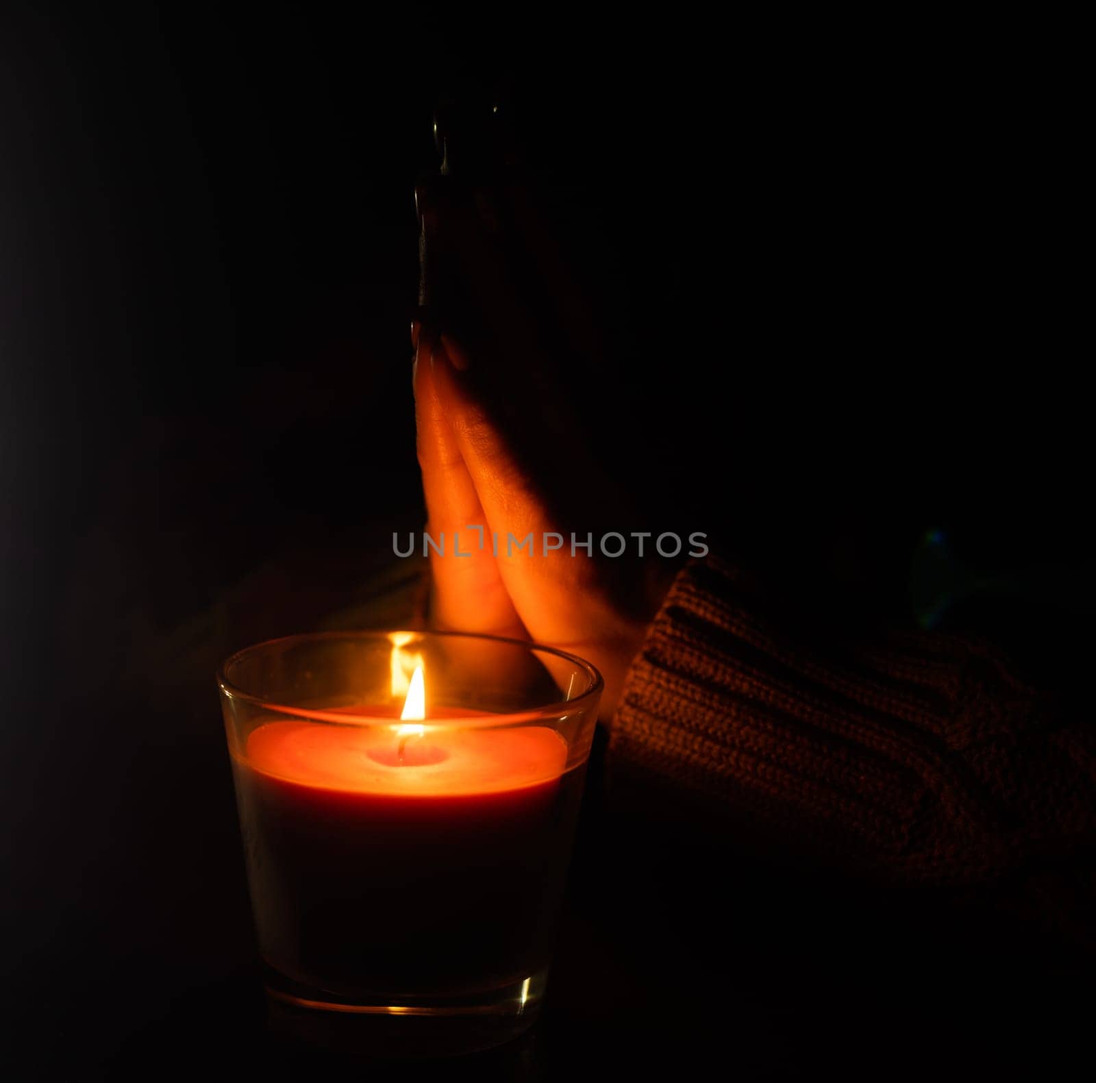 The candle is lit in a glass held by a beautiful woman in black. Isolated on the concept of saving the earth's energy. Earth hour by Andelov13