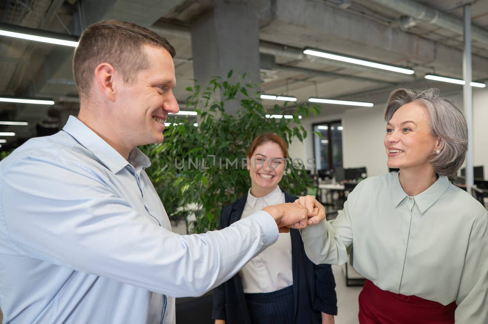 Caucasian man bumping his fists with colleagues as a sign of success. by mrwed54