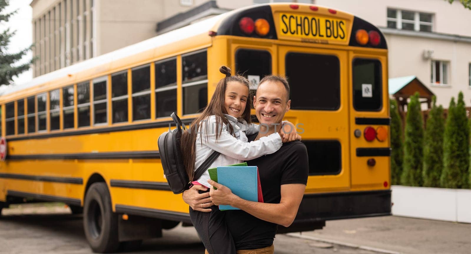 first day at school. father leads a little child school girl in first grade