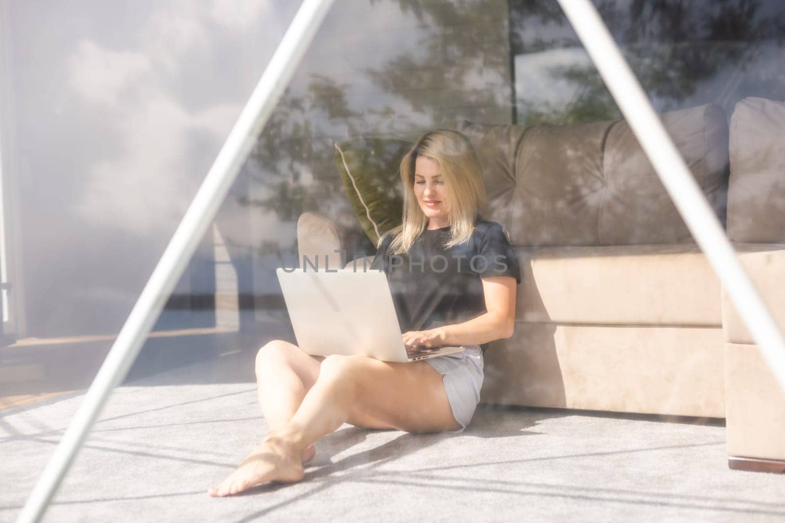 Happy young woman chatting online by using laptop in dome camping. Glamping vacation concept.