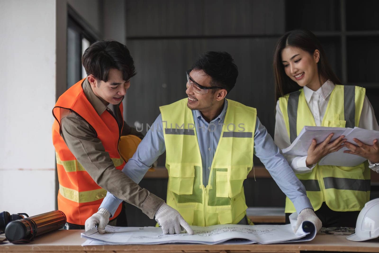 Engineers work as a team with blueprints for architectural plans. Engineer sketching construction project concept with architect equipment Architects talking at table Teamwork and construction concept by wichayada