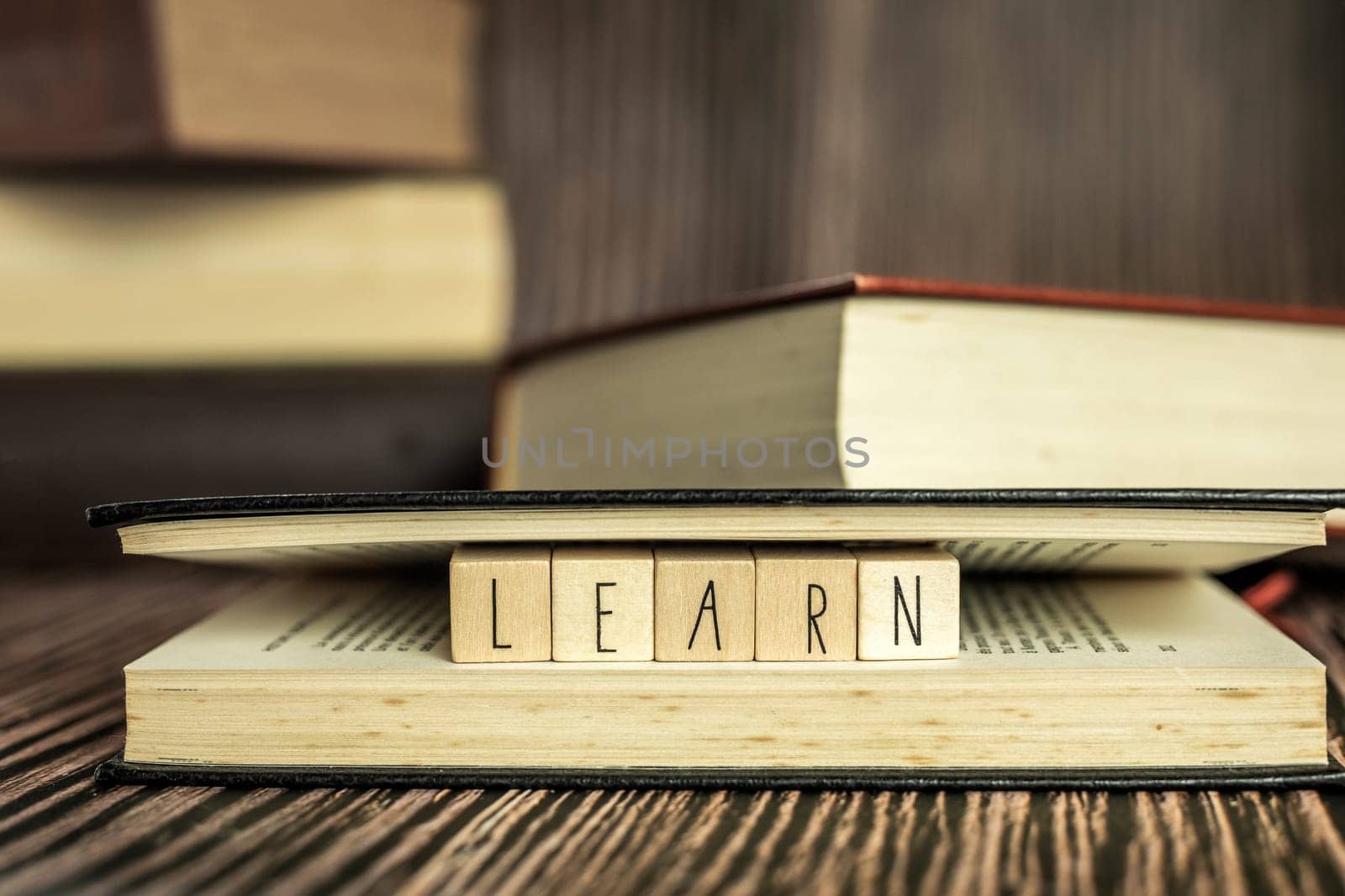 Pile of books, reading. Stack of books in the colored cover lay on the table. Open book with the text learn wooden background, education, reading, learning concept close up