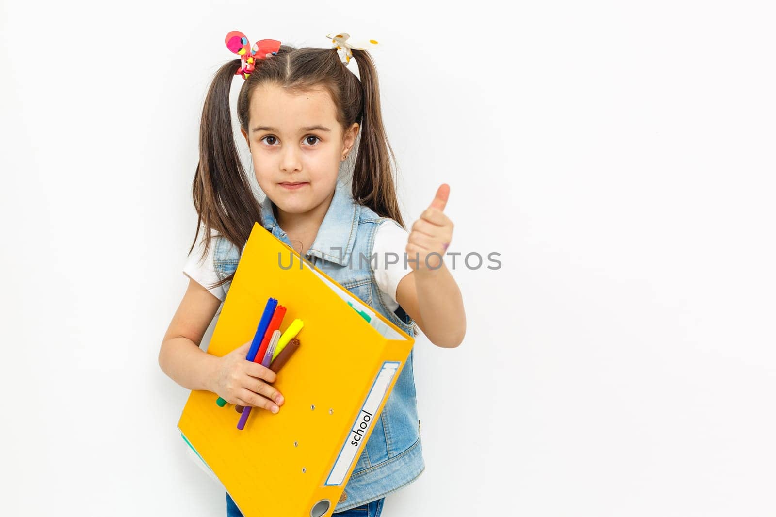 happy sweet little school girl carrying schoolbag backpack and books smiling in education and back to school concept isolated on white background by Andelov13