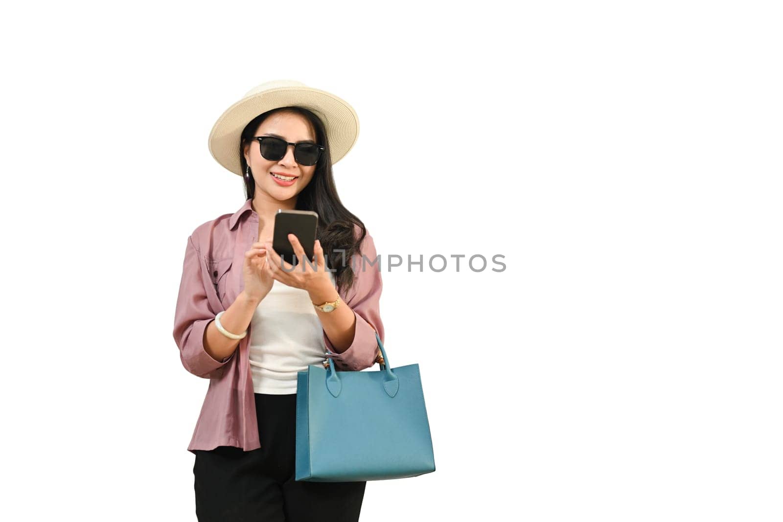 Beautiful female traveler in casual clothes and sunglasses using smartphone isolated on white background.