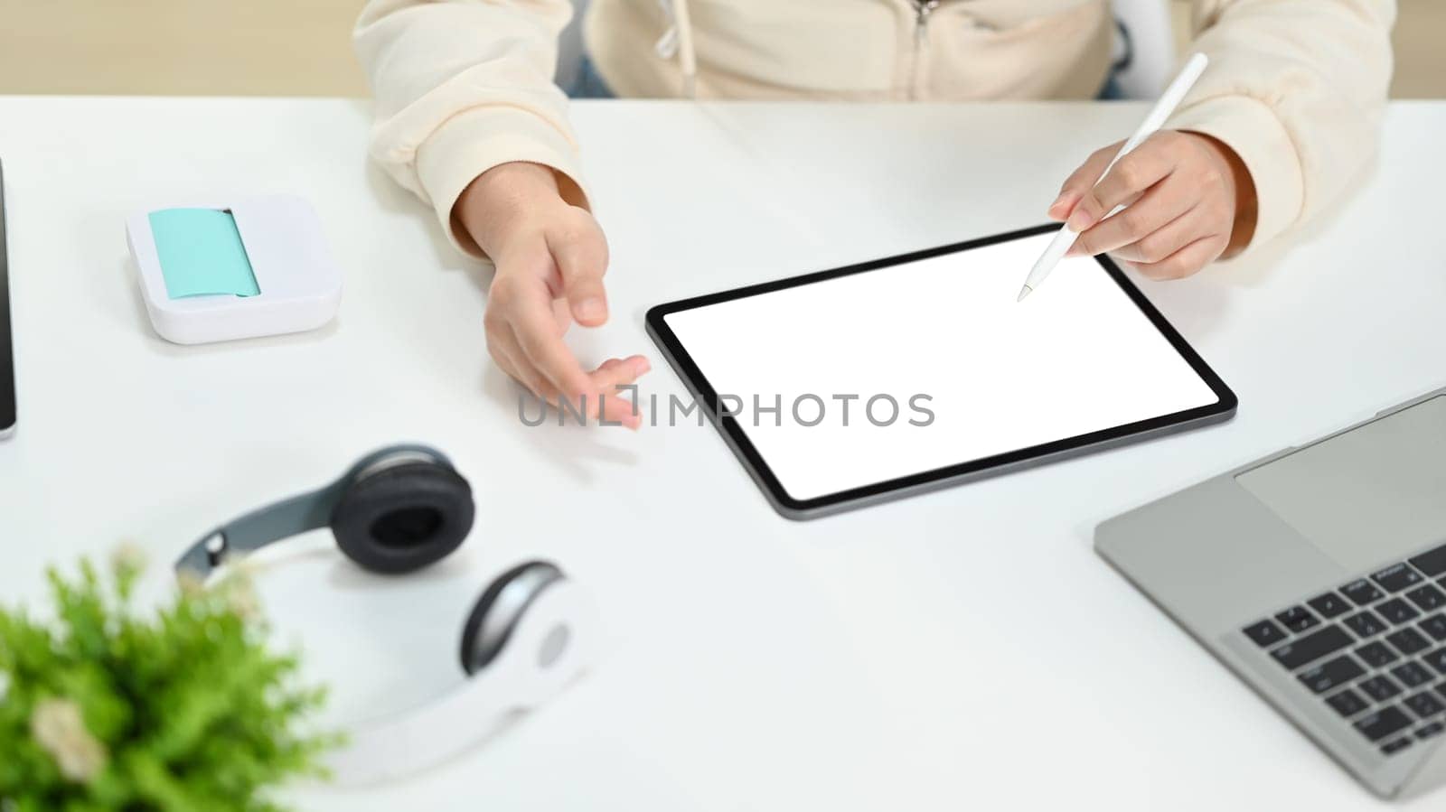 Cropped image of young woman making research, browsing internet via digital tablet at working desk.